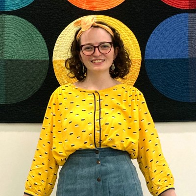 a picture of a smiling white woman with brown hair in a yellow shirt